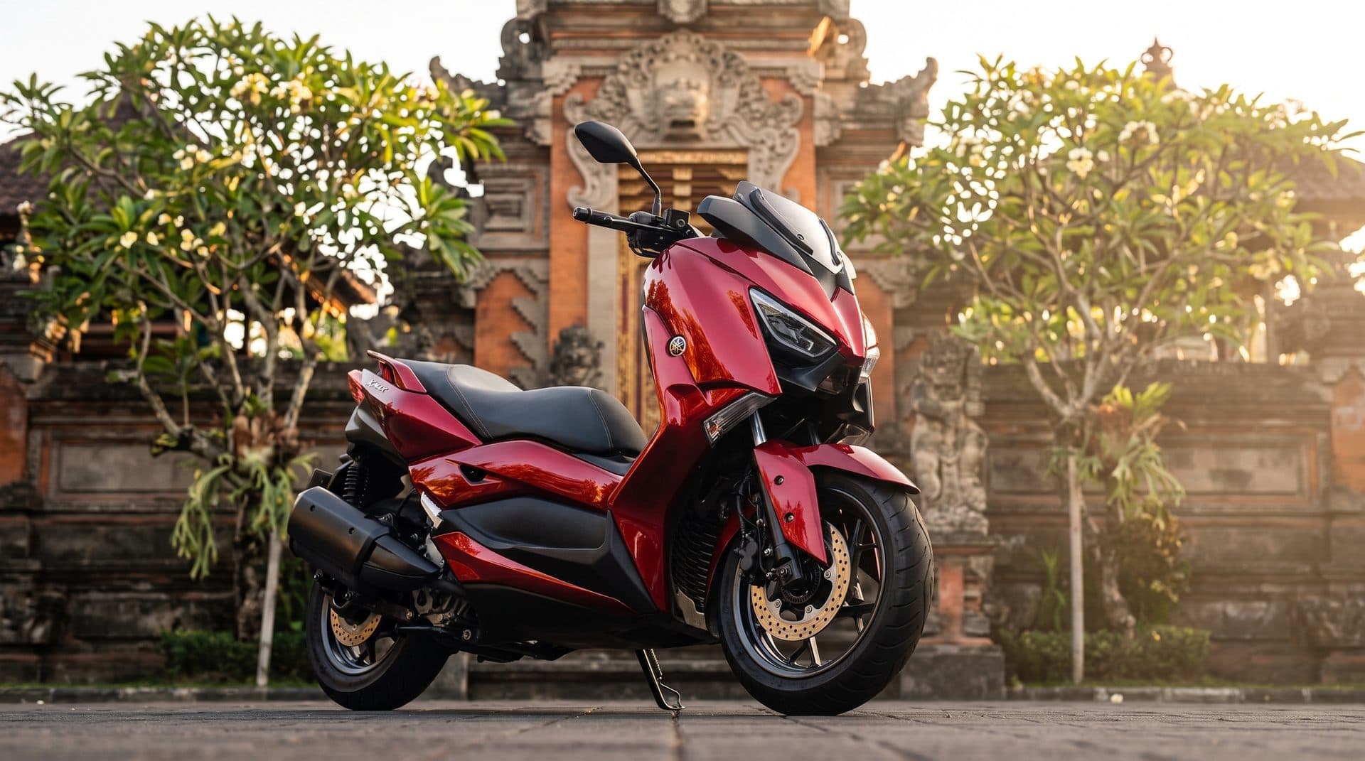 Candy-red Yamaha Xmax in front of a Balinese temple gate at golden hour
